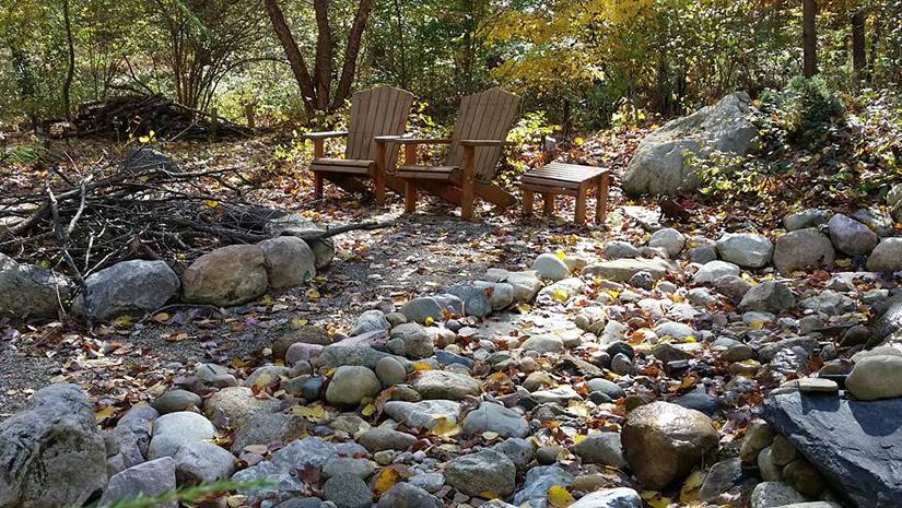 Rocky area in woods with campfire ring two Adirondack chairs