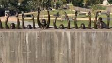 Monumental bronze and cement sculpture of Black people with their hands raised in the air.
