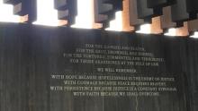 National Memorial for Peace and Justice wall with "We will remember" quote and slabs of metal hanging from above representing lynchings
